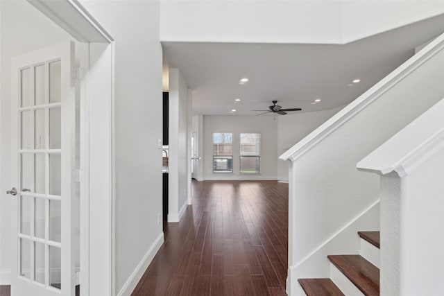 hallway featuring dark wood-type flooring, recessed lighting, baseboards, and stairs