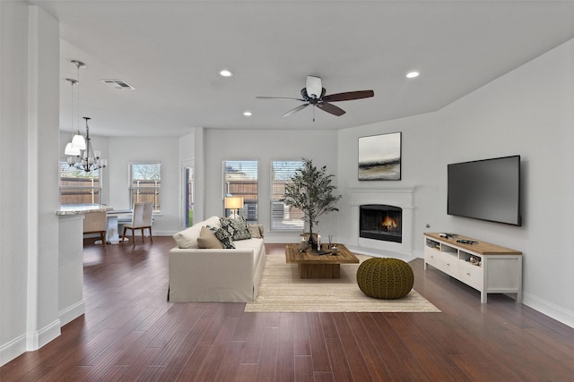 living room featuring a lit fireplace, visible vents, dark wood finished floors, and recessed lighting