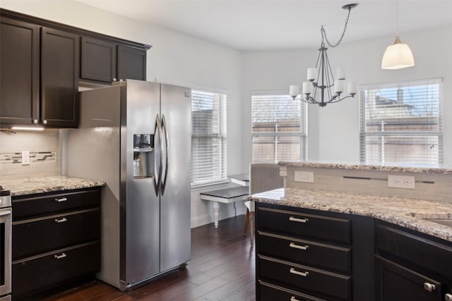 kitchen featuring stainless steel fridge with ice dispenser, light stone countertops, dark wood-style floors, tasteful backsplash, and decorative light fixtures