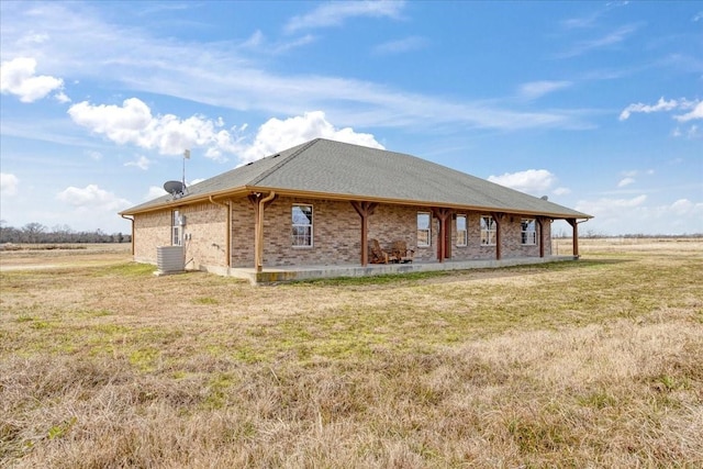 exterior space featuring brick siding, a lawn, and central AC