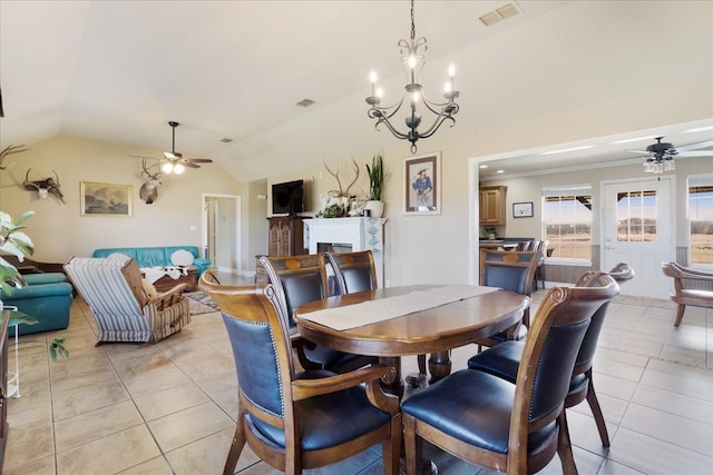 dining space with lofted ceiling, a fireplace, visible vents, and ceiling fan with notable chandelier