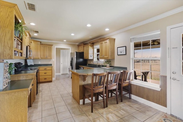 kitchen with visible vents, dark countertops, stainless steel microwave, a peninsula, and a sink