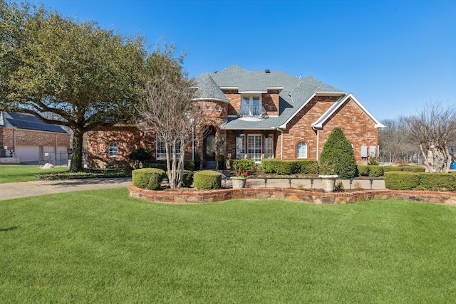 view of front facade featuring brick siding, roof with shingles, and a front yard