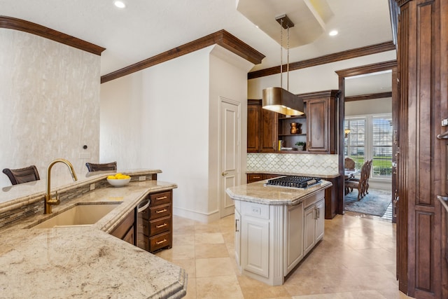 kitchen featuring light stone countertops, a sink, stainless steel gas stovetop, crown molding, and tasteful backsplash