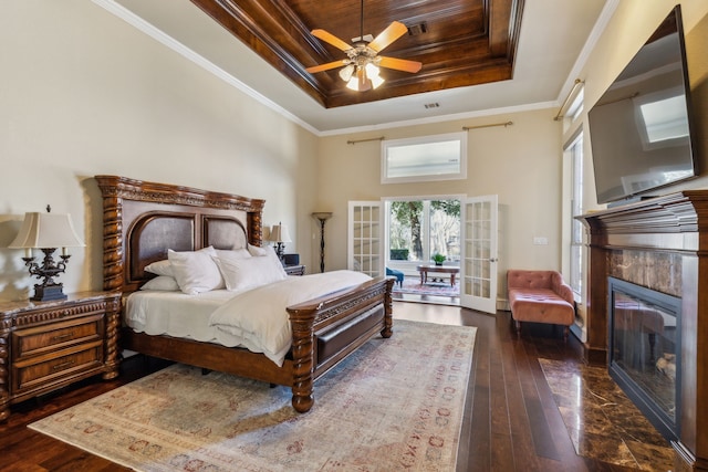 bedroom with dark wood-style floors, french doors, a raised ceiling, and ornamental molding