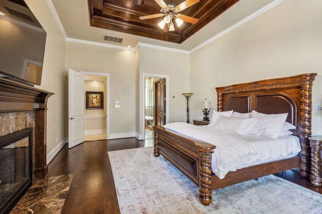 bedroom featuring a tiled fireplace, a raised ceiling, visible vents, and ornamental molding