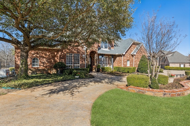 view of front of property with brick siding, driveway, and a front yard