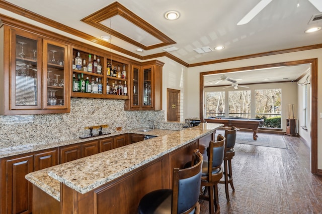 bar with backsplash, crown molding, ceiling fan, wet bar, and a sink