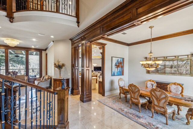 entrance foyer featuring marble finish floor, ornamental molding, a glass covered fireplace, a towering ceiling, and ornate columns