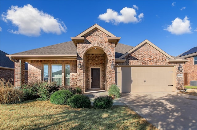 view of front of property featuring driveway, an attached garage, a shingled roof, and brick siding