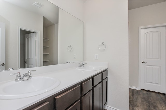 bathroom featuring double vanity, wood finished floors, a sink, and visible vents