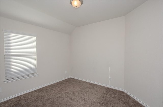 spare room featuring lofted ceiling, carpet, and baseboards