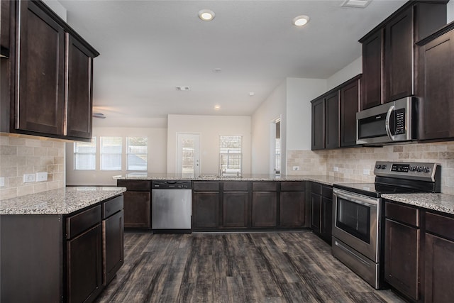 kitchen featuring appliances with stainless steel finishes, dark wood-type flooring, dark brown cabinetry, and a peninsula