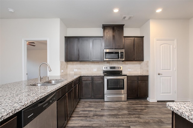 kitchen with light stone counters, dark wood finished floors, visible vents, appliances with stainless steel finishes, and a sink