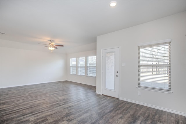 empty room with a ceiling fan, dark wood-style flooring, visible vents, and baseboards