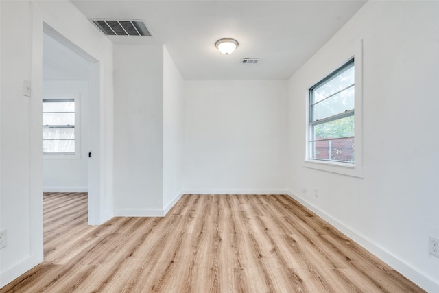 unfurnished room featuring light wood-type flooring, plenty of natural light, and visible vents