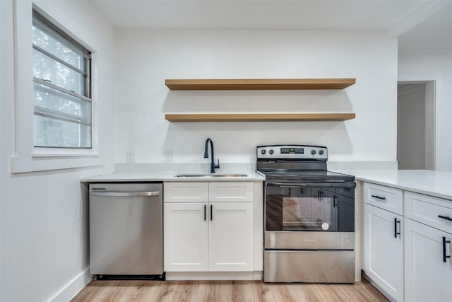 kitchen with appliances with stainless steel finishes, a sink, light wood finished floors, and open shelves