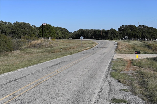 view of street with a rural view and a wooded view