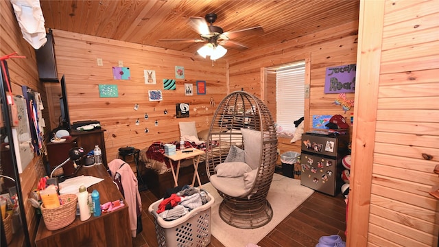 living area featuring ceiling fan, wood walls, wooden ceiling, and wood finished floors