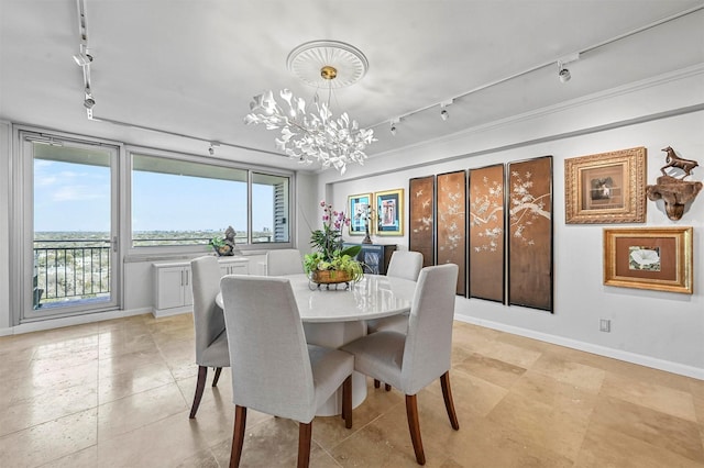 dining space with baseboards, a notable chandelier, and track lighting
