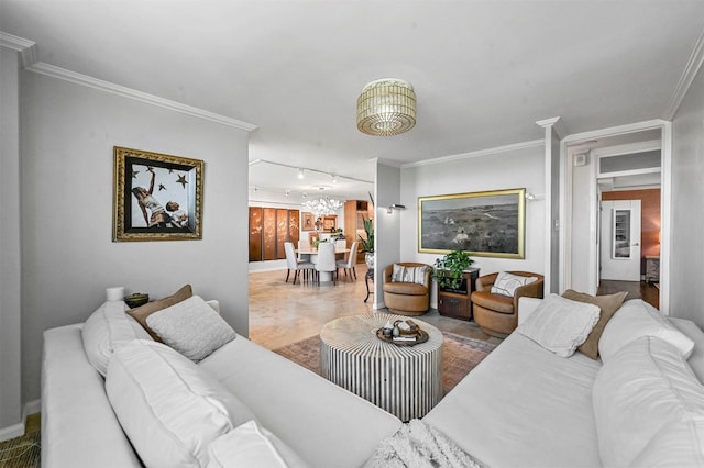 living area with a notable chandelier, ornamental molding, baseboards, and track lighting