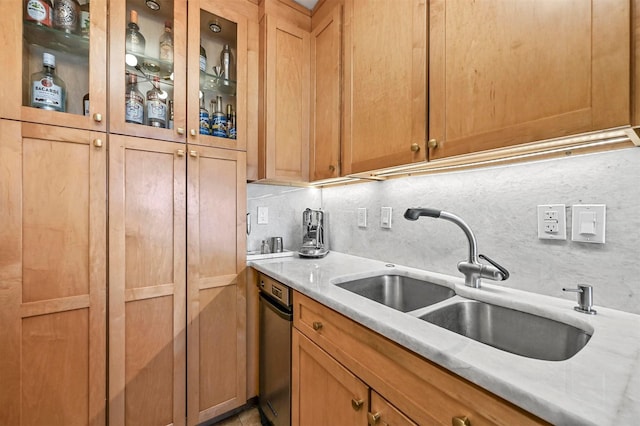 kitchen with light stone counters, glass insert cabinets, a sink, and decorative backsplash
