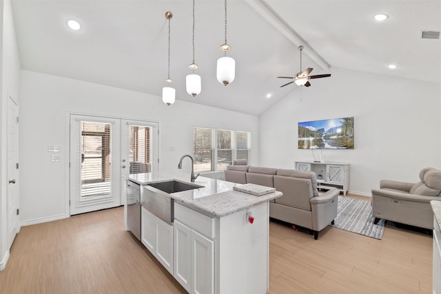 kitchen with visible vents, light wood finished floors, a sink, beamed ceiling, and open floor plan