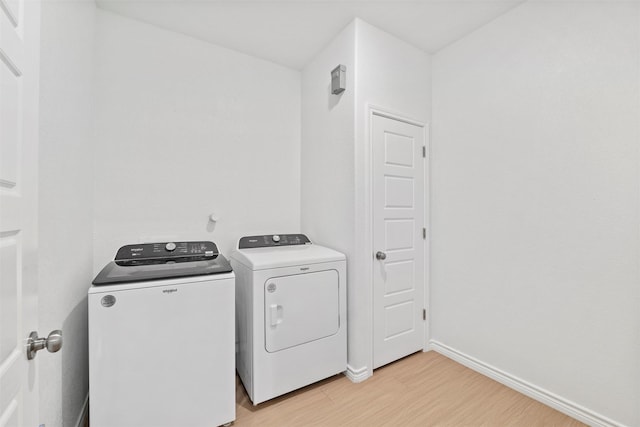 laundry room with laundry area, separate washer and dryer, light wood-type flooring, and baseboards