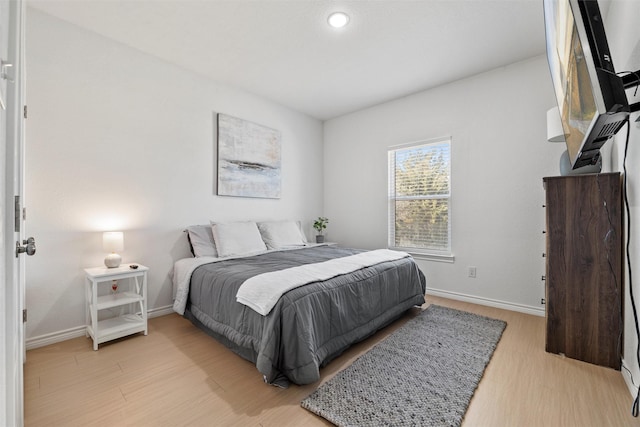 bedroom with light wood finished floors and baseboards