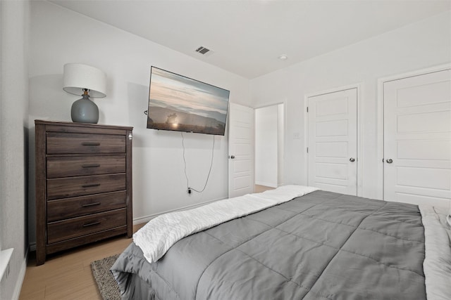 bedroom with light wood-style floors and visible vents