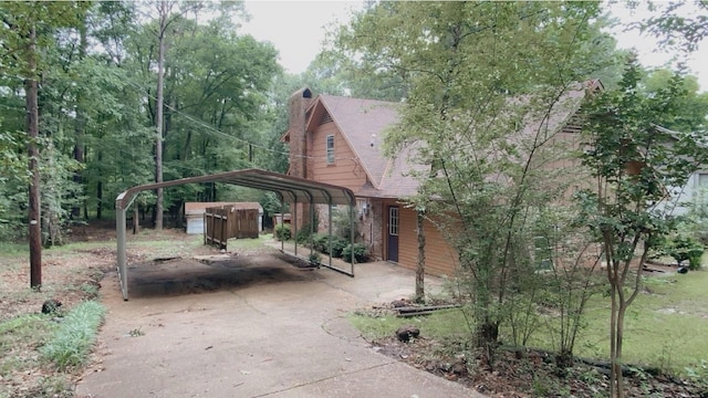 view of property exterior with a carport, roof with shingles, driveway, and a chimney