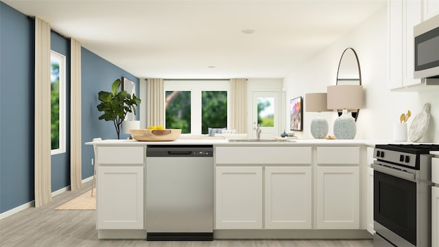 kitchen with stainless steel appliances, light wood-style floors, white cabinets, and a sink