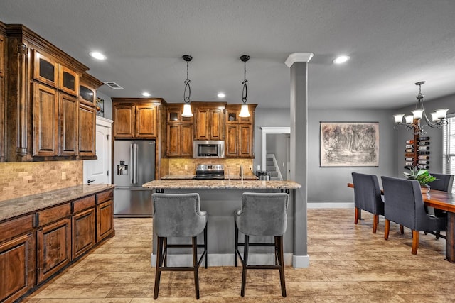 kitchen featuring a breakfast bar, visible vents, appliances with stainless steel finishes, light stone countertops, and glass insert cabinets