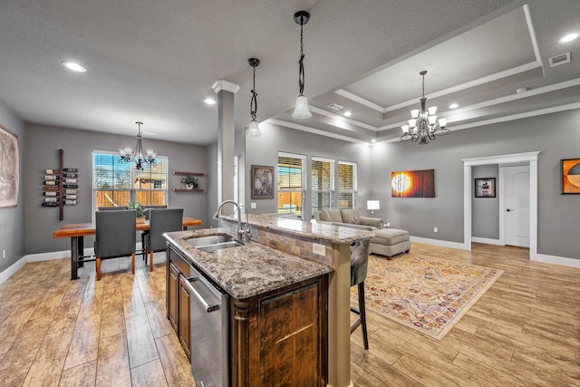 kitchen featuring a tray ceiling, visible vents, an inviting chandelier, light wood-style floors, and a sink