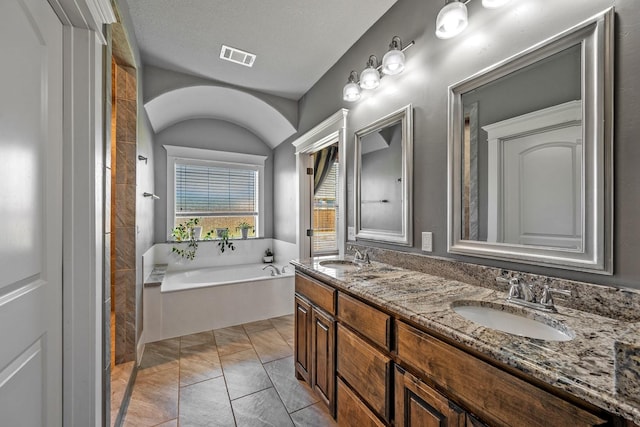 bathroom featuring a bath, double vanity, visible vents, and a sink