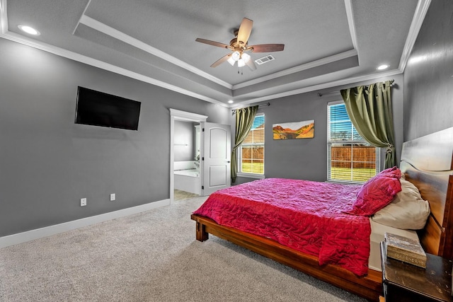 carpeted bedroom featuring a raised ceiling, visible vents, ornamental molding, ensuite bath, and baseboards