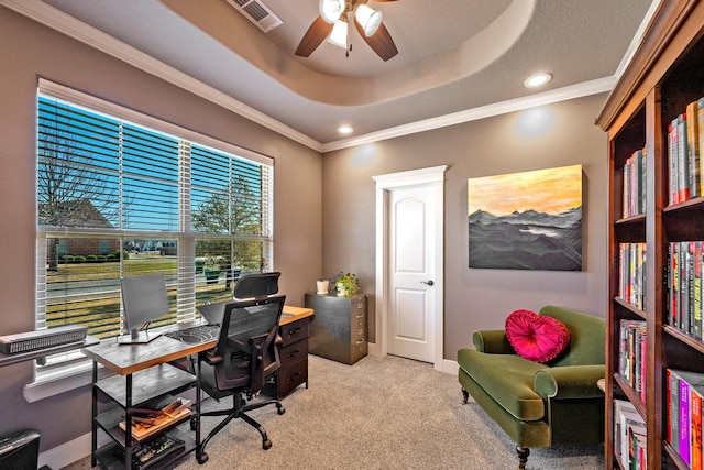 home office featuring light carpet, visible vents, a raised ceiling, a ceiling fan, and ornamental molding