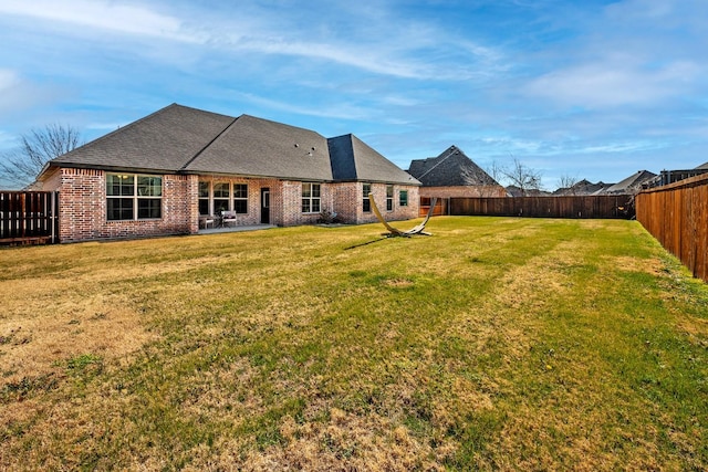 back of house with a patio area, a fenced backyard, a lawn, and brick siding