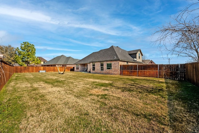 rear view of property with a fenced backyard, a lawn, and brick siding