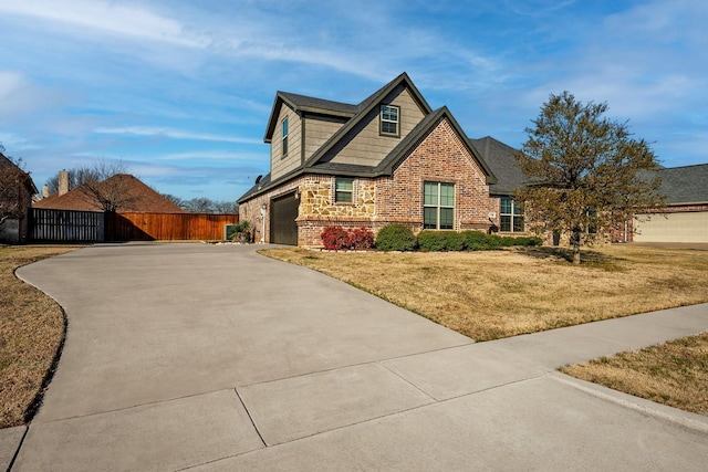 craftsman house with brick siding, an attached garage, a front yard, fence, and driveway