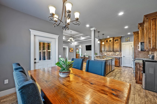 dining room featuring ornamental molding, a tray ceiling, light wood-type flooring, a notable chandelier, and recessed lighting