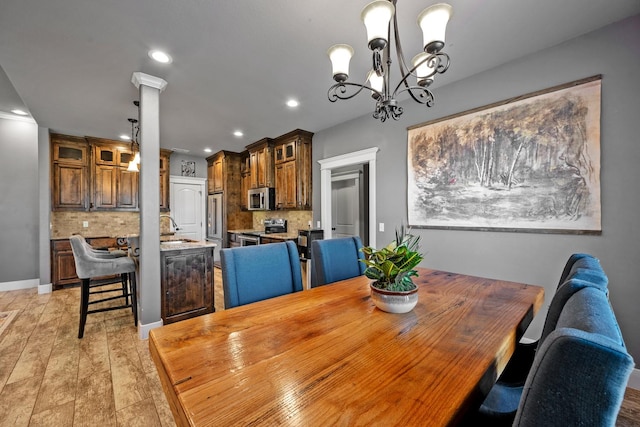 dining area with a chandelier, light wood-style flooring, recessed lighting, baseboards, and decorative columns