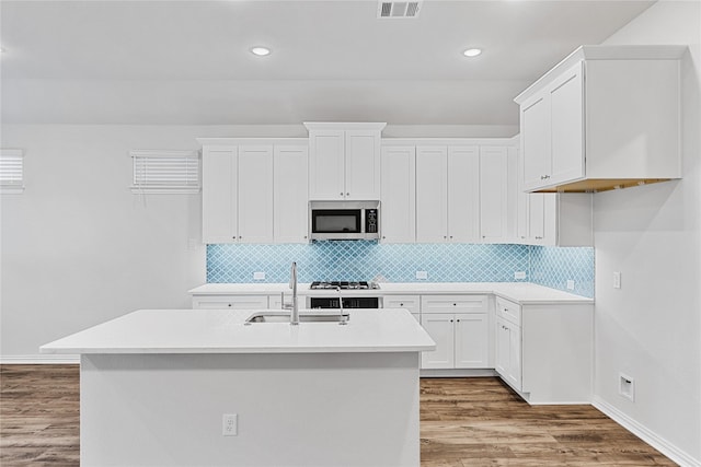 kitchen featuring a sink, visible vents, light countertops, light wood finished floors, and stainless steel microwave