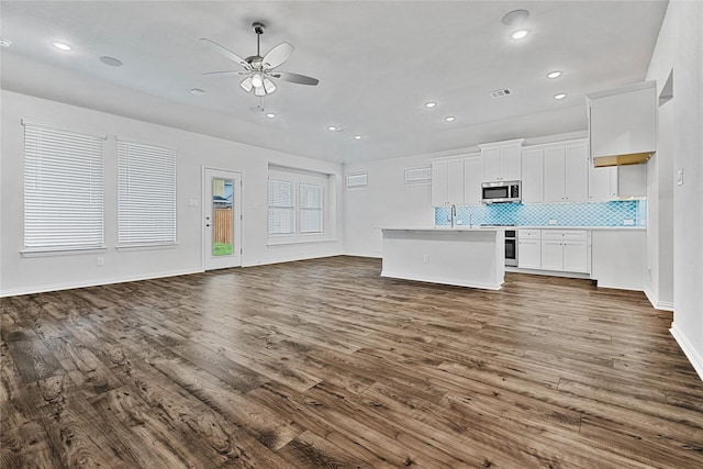 kitchen featuring stainless steel appliances, tasteful backsplash, open floor plan, and dark wood-style floors