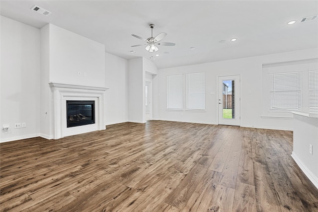 unfurnished living room with a glass covered fireplace, wood-type flooring, visible vents, and ceiling fan