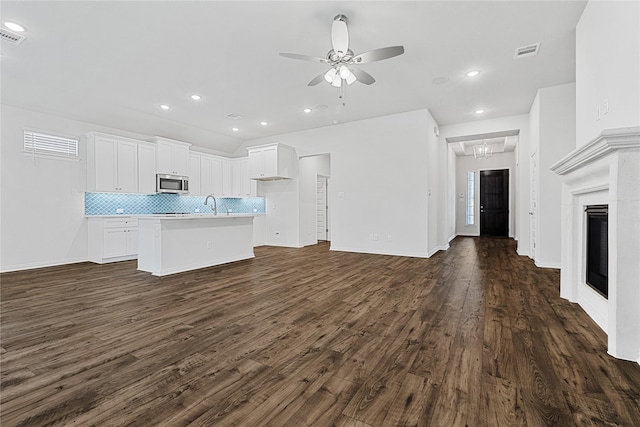 kitchen featuring tasteful backsplash, visible vents, stainless steel microwave, open floor plan, and dark wood-type flooring