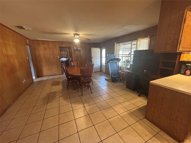 dining space featuring ceiling fan, wooden walls, visible vents, and light tile patterned floors