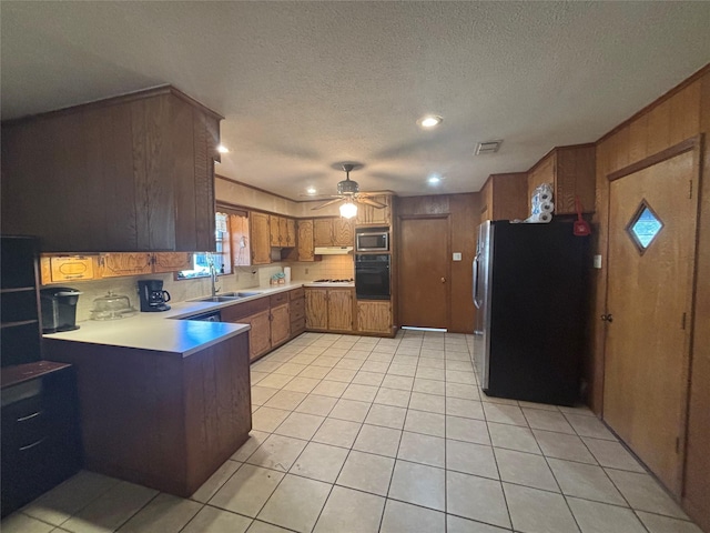 kitchen with stainless steel appliances, a peninsula, visible vents, light countertops, and brown cabinets