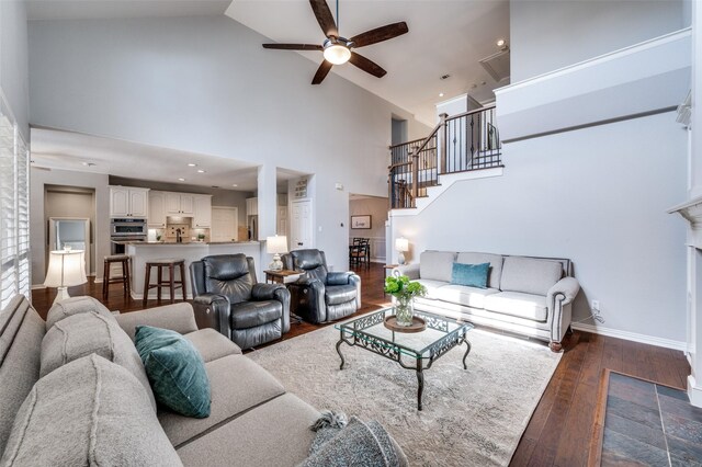 living room featuring stairs, high vaulted ceiling, dark wood finished floors, and baseboards