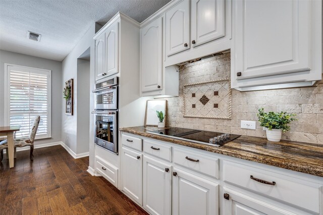 kitchen featuring white cabinets, dark stone counters, dark wood finished floors, black electric cooktop, and double oven